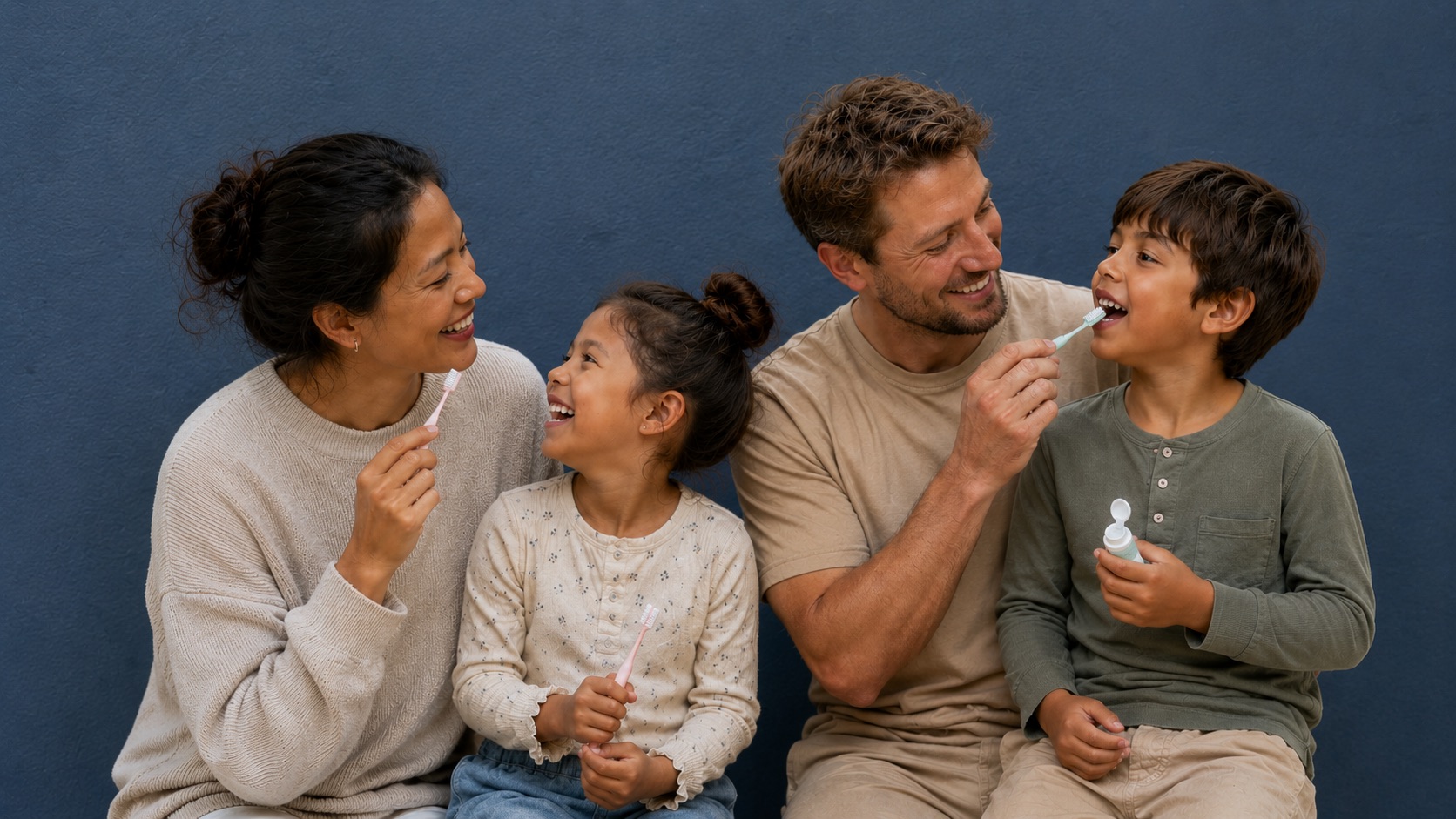 Familie mit zwei Kindern putzt sich gemeinsam lachend die Zähne