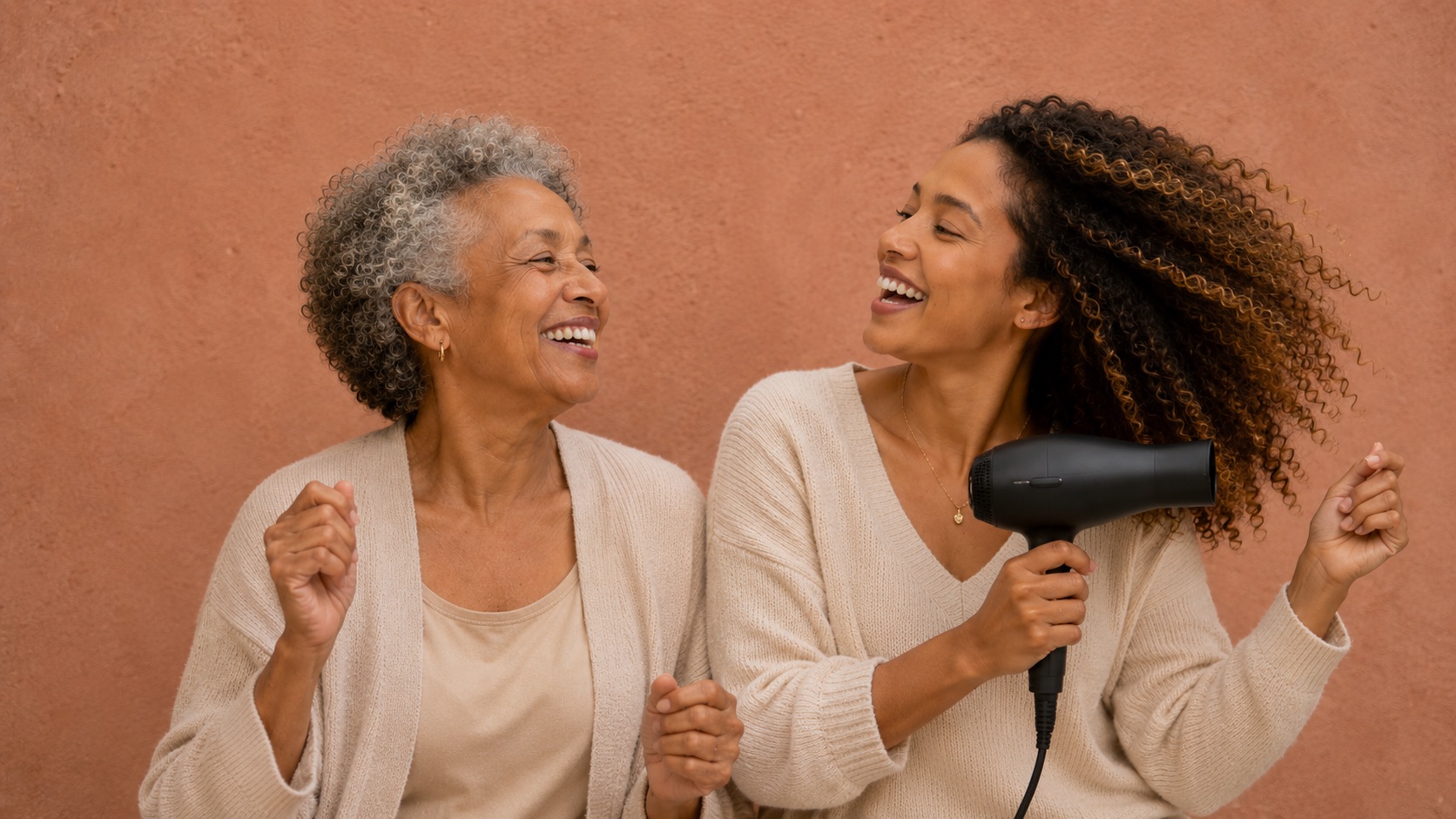 Ältere Mutter und erwachsene Tochter lachen beim Haareföhnen