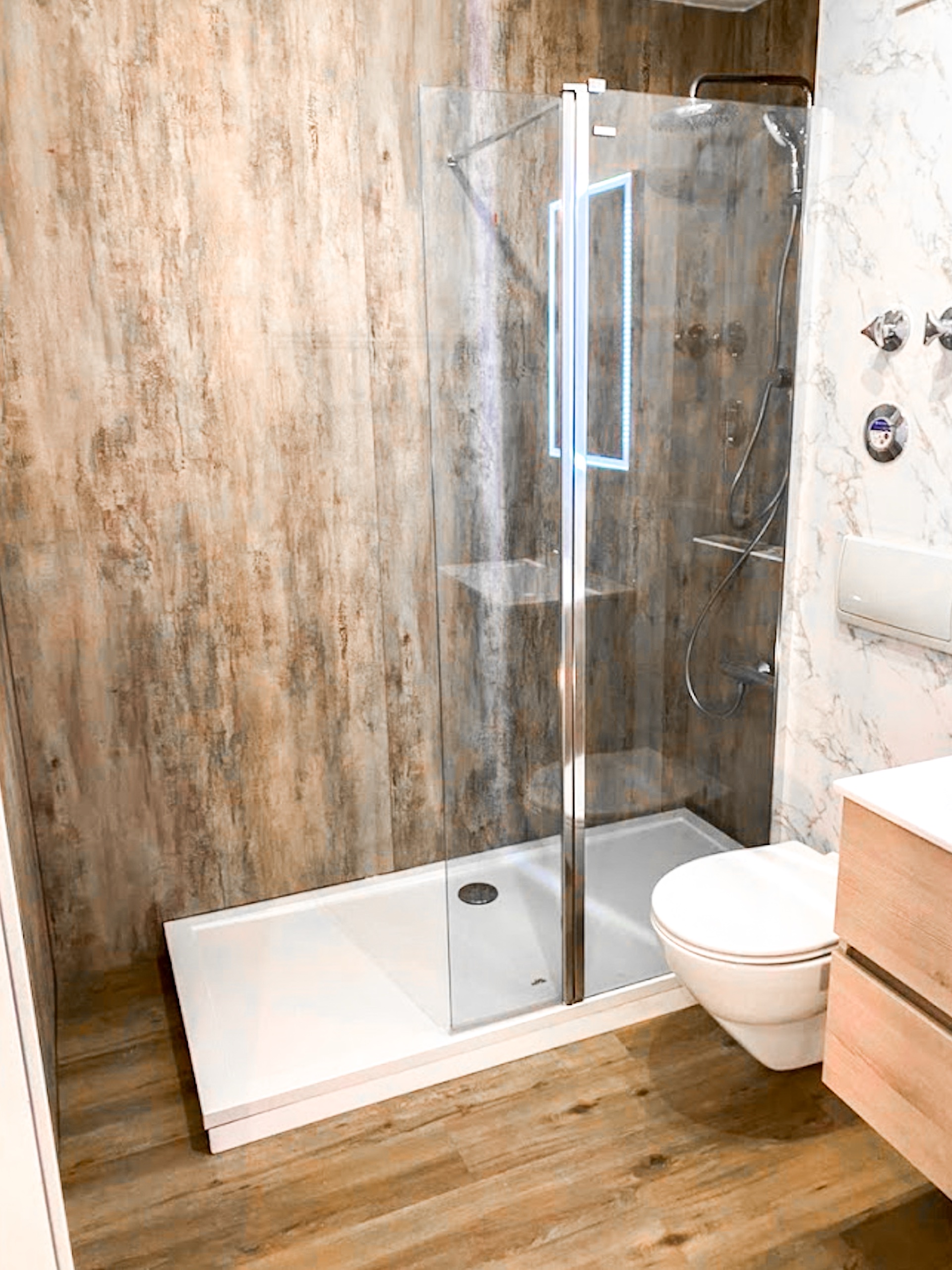Dusche mit Wandpaneelen in rustikaler Steinoptik und Glasabtrennung